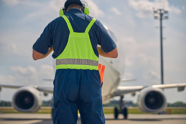 Trabajador del aeropuerto en uniforme encontrando un avión - Foto, imagen