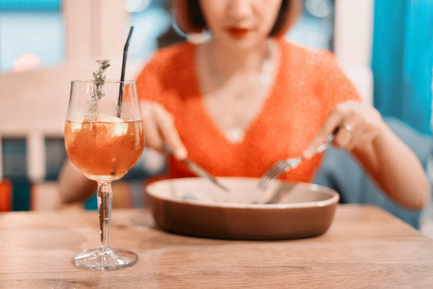 Asian woman drinks delicious cocktails in a restaurant and eats food from the chef. Rest and celebration in a cafe - Photo, Image