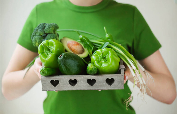 Korkea kulma nimetön nainen vihreä t paita osoittaa säiliö kypsä terveellisiä vihanneksia - Valokuva, kuva