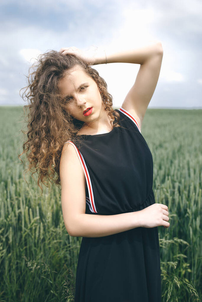 Longhaired Pretty Girl In Black Dress Standing On The Green Field. - Foto, afbeelding