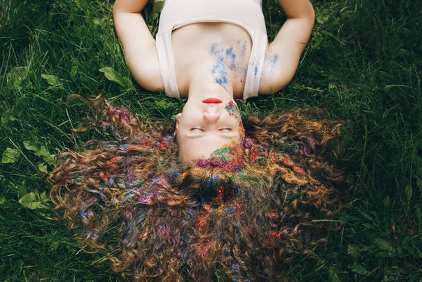 Una bella ragazza con i capelli ricci sdraiati sull'erba con gli occhi chiusi - Foto, immagini