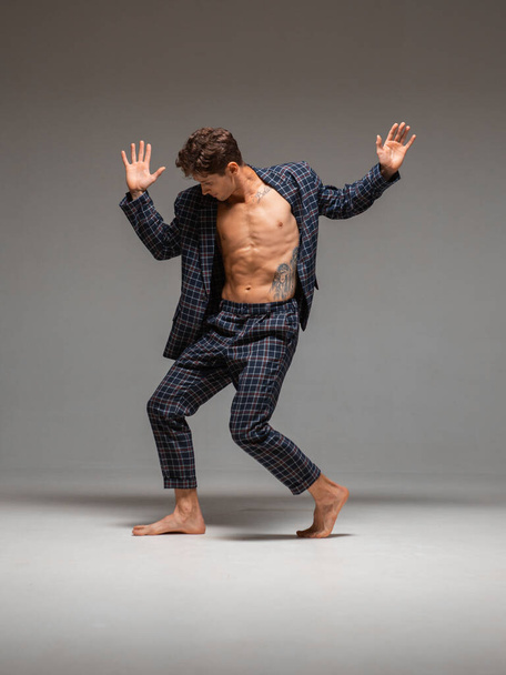 Stylish young man dancer in suit dancing modern dance with naked torso barefoot in studio. Dance lessons - Foto, Imagem
