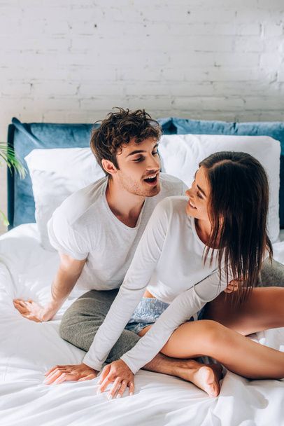 Young couple sitting on bed and looking at each other - Фото, изображение