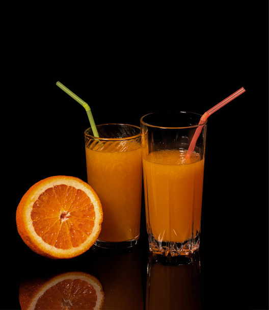 Ποτήρι με φρέσκο χυμό πορτοκαλιού και πορτοκάλι σε μαύρο φόντο - Φωτογραφία, εικόνα