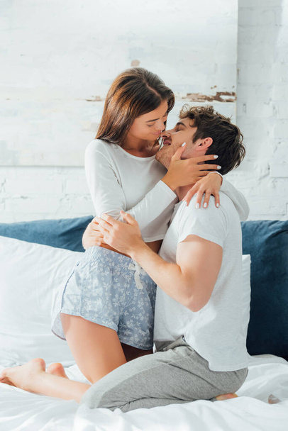 Selective focus of young couple kissing and hugging on bed  - Photo, Image
