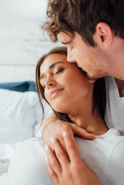 foyer sélectif de l'homme avec les yeux fermés embrasser petite amie sur le lit  - Photo, image