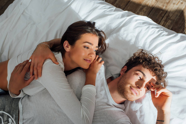 High angle view of couple in pajamas lying on bed at morning  - Foto, Bild