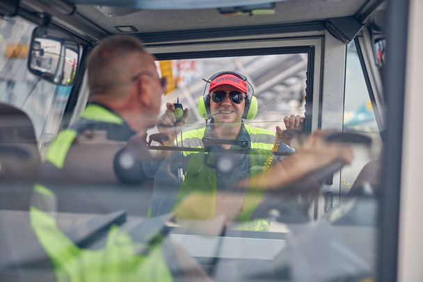 Ο επόπτης χαμογελαστού αεροσκάφους μιλάει σε οδηγό φορτηγού - Φωτογραφία, εικόνα