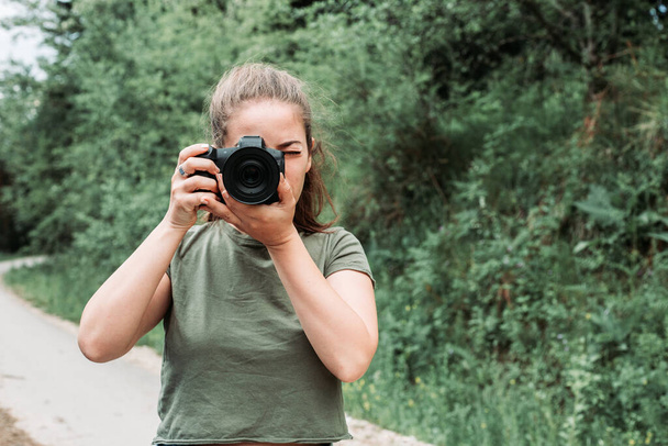 Cute, brunette girl taking photos with her camera. Outdoor photo, nature - Photo, Image