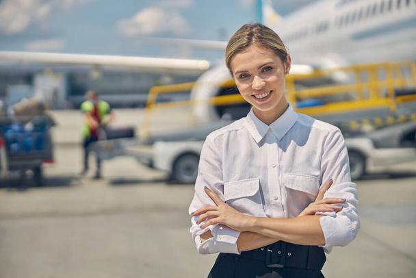Smiling stylish airline employee is standing outdoors - Φωτογραφία, εικόνα