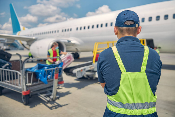 Manipuladores de equipaje cargando maletas en un avión - Foto, imagen