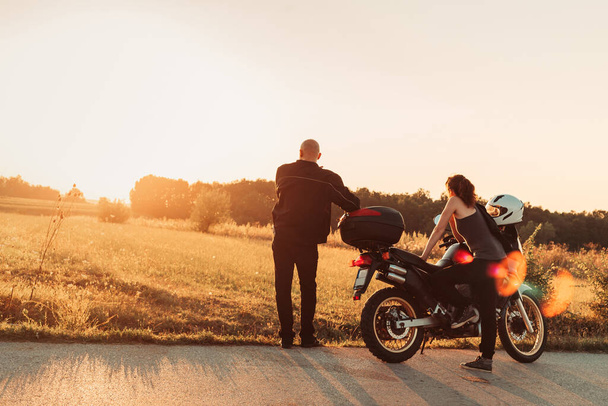 Bikers couple taking a rest on the road. Afternoon light, copy space - 写真・画像