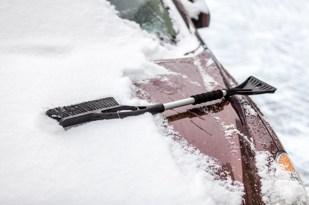 Черная кисть лежит на машине покрытой снегом
 - Фото, изображение