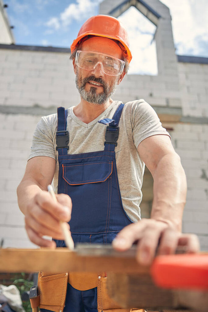 Güvenlik gözlüklü marangoz düz bir çubuk kullanıyor. - Fotoğraf, Görsel