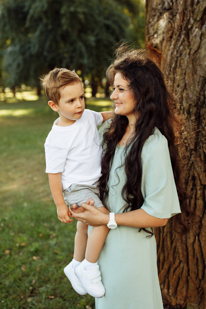Gelukkig jong moeder met jongen in het park - Foto, afbeelding