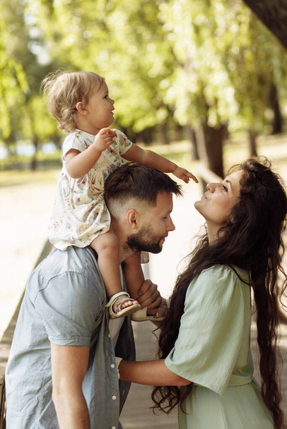Happy young mother and father  with girl  in the park - Φωτογραφία, εικόνα