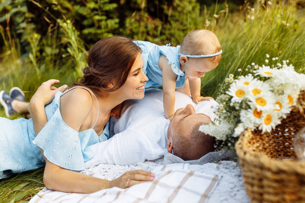 beautiful  couple  with baby girl  having picnic  in garden.  - Fotó, kép