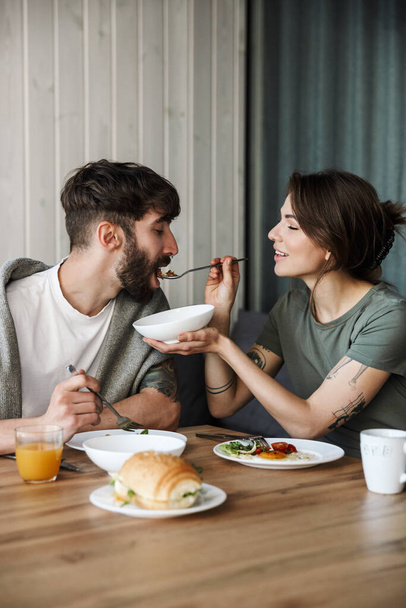 Lovely young couple having healthy breakfast in the kitchen, feeding - Foto, Imagem