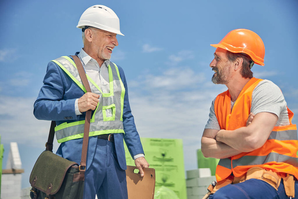 Веселый старший мужчина улыбается строителю - Фото, изображение