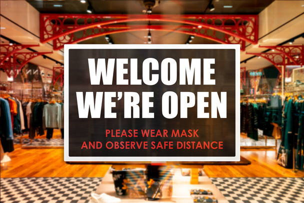 Maske takmayı ve mesafeyi gözlemeyi hatırlatan bir butik mağazasının hoş geldin işareti. Bir barda veya restoranda yeni normal işlemler kavramı. - Fotoğraf, Görsel