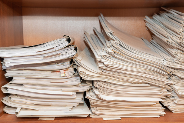 Старые бумажные документы, сложенные в архив. Документы на полках архивной комнаты. Полки в шкафу, заполненные файлами - Фото, изображение