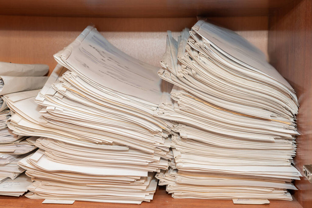 Alte Papierdokumente stapeln sich im Archiv. Dokumente in den Regalen des Archivraums. Büroregale im Schrank voller Akten - Foto, Bild