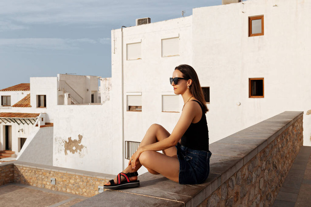 Όμορφη νεαρή γυναίκα απολαμβάνει ελεύθερο χρόνο στην παραλία του παραδείσου στην Ισπανία.Νεαρό κορίτσι στη βεράντα με μπλε θάλασσα και ουρανό στο παρασκήνιο. - Φωτογραφία, εικόνα