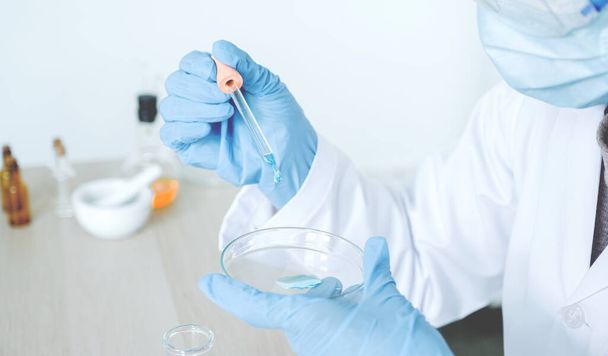 Les scientifiques tiennent la pipette et laissent tomber le liquide chimique bleu pour la recherche et l'analyse dans un laboratoire. - Photo, image