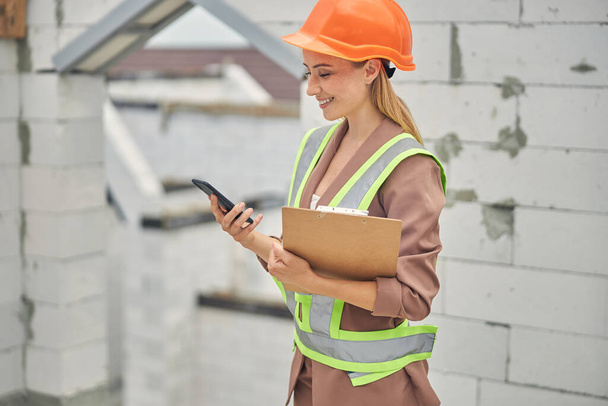 Mujer rubia agradable ingeniero sosteniendo un portapapeles - Foto, Imagen