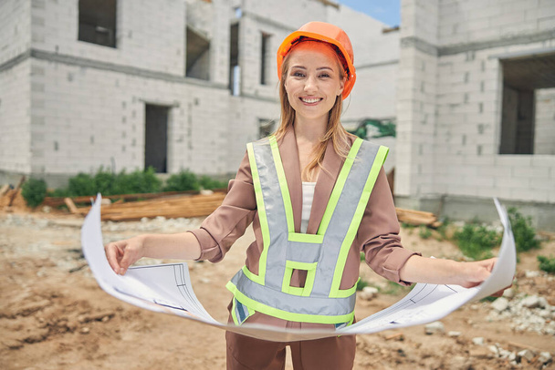 Young woman in a helmet holding a home plan - Photo, Image