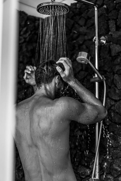 Man taking a shower washing hair with shampoo product under wate - Foto, afbeelding