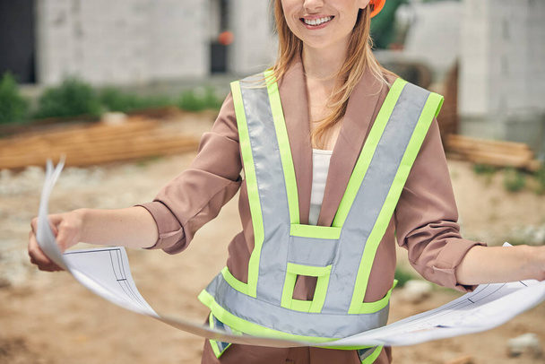 Smiling engineer with blueprints at the construction site - Photo, Image