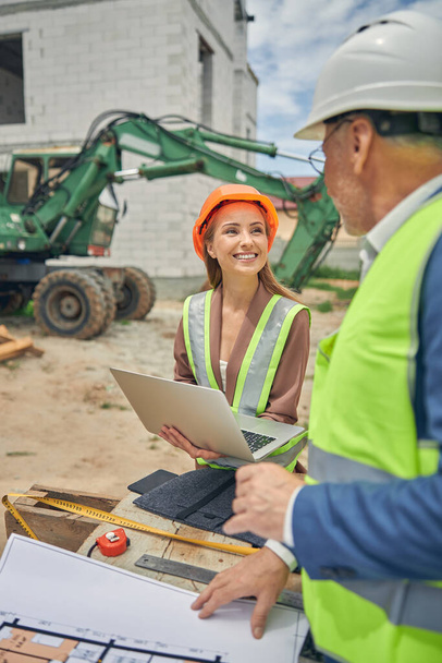 Woman in a hard hat communicating with her colleague - Photo, Image