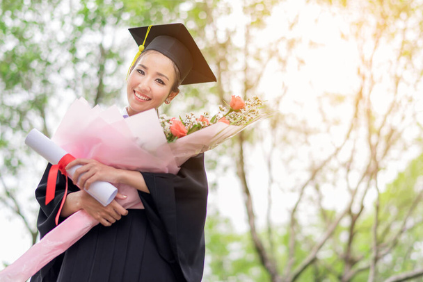 Απόφοιτη φοιτήτριες φορώντας καπέλο αποφοίτησης και φόρεμα με αίσθημα ευτυχίας με φόντο πάρκο - Φωτογραφία, εικόνα