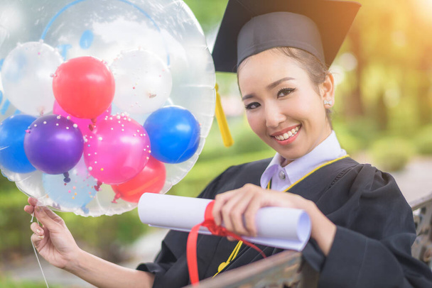 Graduated woman students wearing graduation hat and gown with happiness feeling with park background - Photo, Image