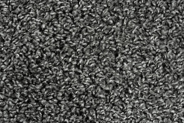 Schwarzer natürlicher Fleece Teppich Textur Hintergrund. Textur aus dunkler Wolle. Fragment graue struppige Matte - Foto, Bild