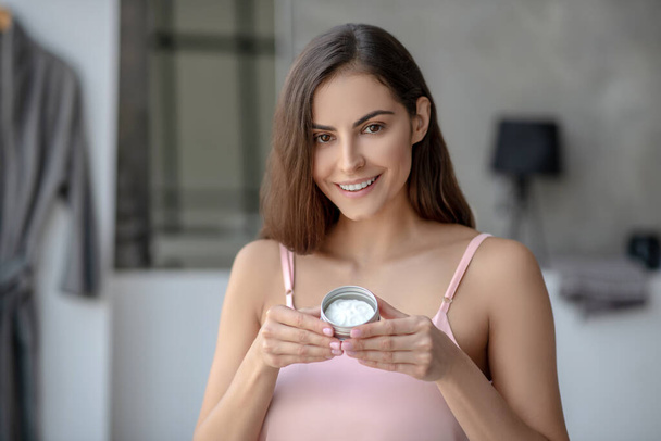 Beautiful woman a jar of skin cream and looking pleased - Photo, Image