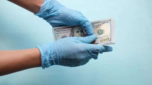 Potilas lahjoo tohtoria. Käsien lähikuva antaa rahaa lääkärille sinisellä pohjalla. Lääkäri ottaa lahjuksia opiaattien määräämisestä, kirjoittaa vääriä lääketieteellisiä raportteja - Materiaali, video
