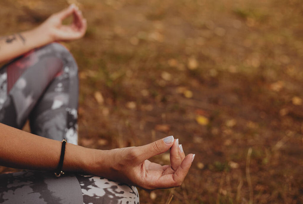 Zbliżenie gest ręki kobiety, która robi pozycji jogi lotosu na zewnątrz, aktywność, aby pozostać fizycznie, psychicznie i duchowo zdrowe. - Zdjęcie, obraz