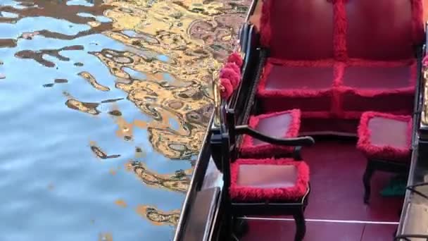 4K. Gondola zaparkovala na kanále v italských Benátkách. Červená sedadla se zlatými ozdobami. - Záběry, video