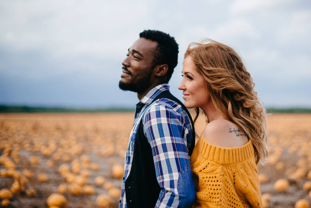 Couple stands in pumpkin field. - Фото, зображення