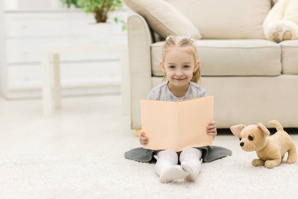 Photo of sweet happy little girl reading a book. - Fotografie, Obrázek