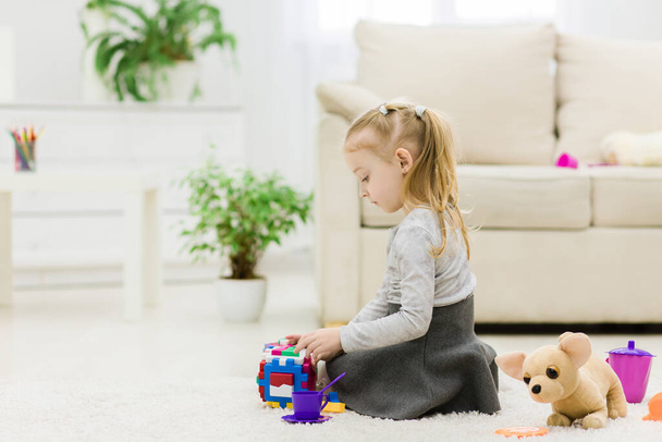 Cute funny preschooler little girl playing with construction toy blocks building a tower in a sunny room. - Foto, Imagem