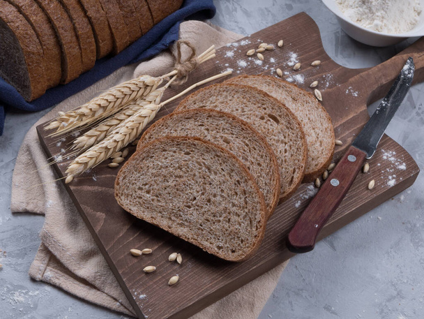 свіжий чорний хліб на дерев'яному столі. Домашній хліб кисломолочний, сільський запечений хліб у плетеному кошику. Свіжоспечений традиційний хліб на дерев'яному столі
 - Фото, зображення