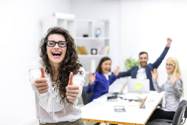 Photo of businesswoman showing thumb-ups in front of her team. - Photo, image
