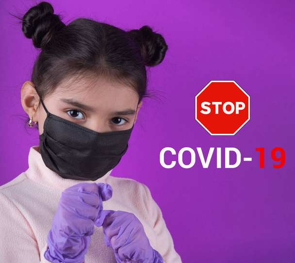 Cute girl with stethoscope and black mask on purple background. Stay home. Stop covid-19. Dispasoble mask. Virus protection equipment. Quarantine. Girl plays a doctor. education and occupation concept. black mask - Photo, Image