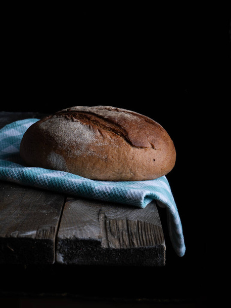 świeży chleb na drewnianym stole na czarnym tle - Zdjęcie, obraz