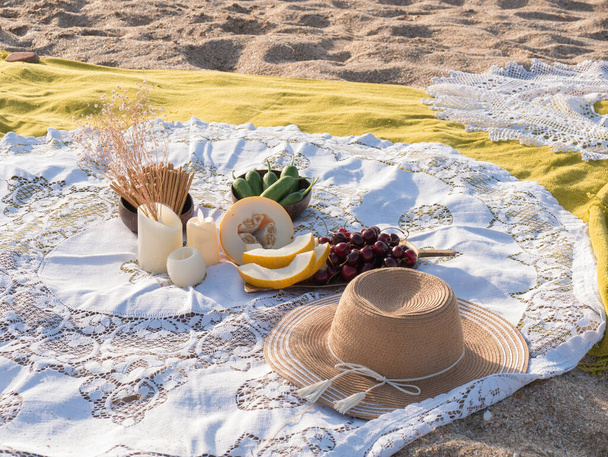 美しい夏のピクニックビーチで日没時にbohoスタイルで。リネンブランケット上の有機新鮮な果物。週末のピクニックのためのベジタリアンエコアイデア.  - 写真・画像