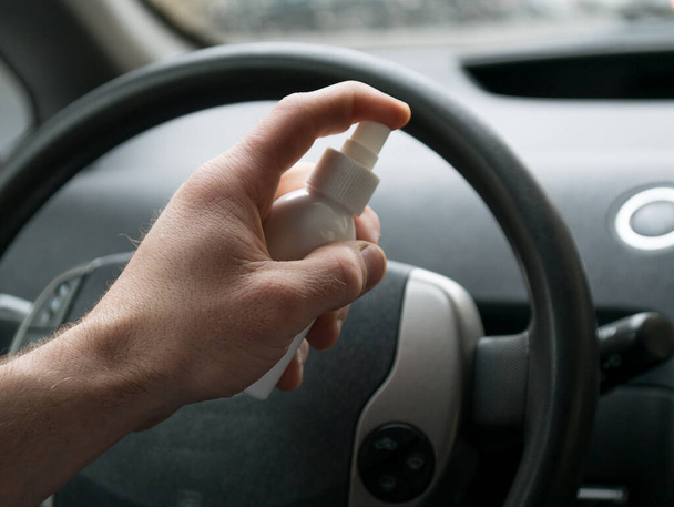 alkoholos gél tiszta mosás kézfertőtlenítő antivírus korona vírus vagy COVID-19 a kormány autó háttér. férfi használ kéz fertőtlenítő a kezét az autóban. - Fotó, kép