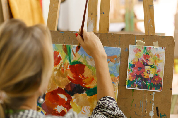 Close-up artist paints a picture on canvas with oil paints. - Photo, image